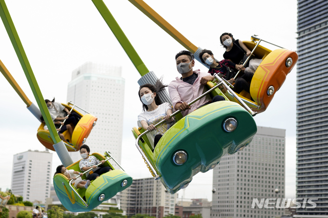 [요코하마=AP/뉴시스] 일본 수도권 요코하마에 있는 놀이공원을 20일 찾은 시민들이 코로나19 예방을 위해 마스크를 착용한 채 놀이기구 문어다리를 타고 스릴을 만끽하고 있다. 일본 정부는 내달 도쿄올림픽 개막을 앞두고 21일부로 도쿄도를 비롯한 9개 도도부현에 발령한 긴급사태 선언을 해제한다.  2020.06.20
