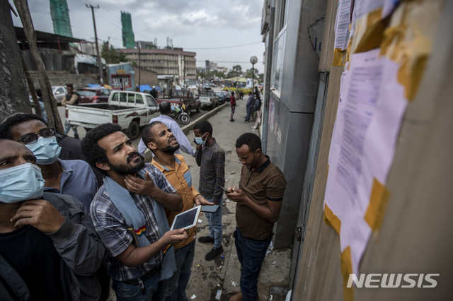 [아디스아바바=AP/뉴시스]에티오피아 사람들이 총선 다음날인 22일(현지시간) 수도 아디스아바바의 한 투표소 밖에 붙은 벽보를 읽고 있다.  