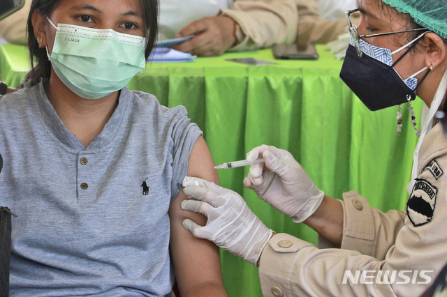 [메단=AP/뉴시스]24일(현지시간) 인도네시아 수마트라섬 동북부 메단에서 인도네시아군이 대규모 백신 접종을 시행해 한 주민이 시노백 백신을 접종하고 있다. 인도네시아는 2022년 3월까지 인구 2억7000만 명 중 1억8100만 명 이상을 접종 목표로 하고 있으나 백신 공급 제한과 국가보건시스템의 미숙 등으로 진행이 더뎌지고 있다. 2021.06.24.