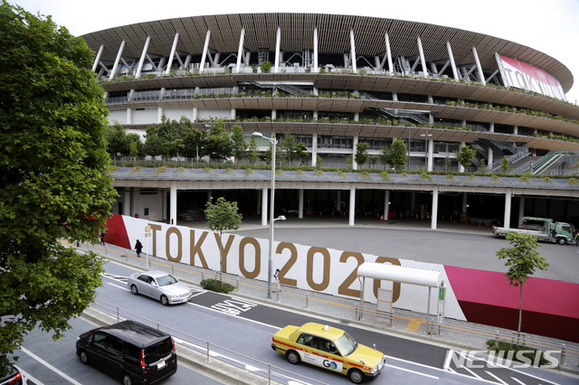[도쿄=AP/뉴시스]지난 29일 도쿄올림픽 경기가 열릴 일본 도쿄 국립경기장의 앞으로 차들이 지나가고 있다. 도쿄올림픽은 내달 23일 개막한다. 2021.06.30. 