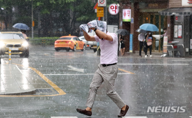 [서울=뉴시스]이영환 기자 = 대기불안정에 의해 소나기가 내린 지난 30일 오후 서울 종로구 세종문화회관 일대에서 한 시민이 신문을 머리에 쓰고 비를 피해 발걸음을 옮기고 있다. 2021.06.30. 20hwan@newsis.com