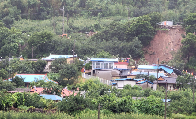 [광양=뉴시스] 변재훈 기자 = 6일 오전 전남 광양시 진상면 한 야산에서 산사태가 발생해 인근 민가 4채 중 2채가 매몰되고 2채가 반파됐다. 소방당국은 실종자 1명을 구조·수색하고 있다. 사진은 건너편 도로에서 바라본 산사태 현장. (사진=독자 제공) 2021.07.06. photo@newsis.com