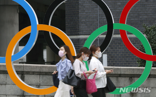 [도쿄=AP/뉴시스] 지난 8일 일본 도쿄에서 코로나19 확산 방지를 위해 마스크를 쓴 사람들이 도쿄 올림픽 오륜 조형물 앞을 지나가고 있다. 2021.07.09.