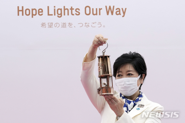 [도쿄=AP/뉴시스]9일 일본 도쿄도 세타가야구 고마자와 올림픽 공원에서는 도쿄올림픽 성화 릴레이가 시작되기 전 기념식 열렸다. 기념식에 참석한 고이케 유리코 도쿄도지사가 성화가 든 등불을 들어보이고 있다. 2021.07.09.
