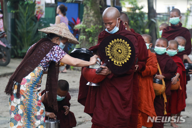 [양곤(미얀마)=AP/뉴시스]지난 15일 오전 마스크 쓴 승려들이 신자들로부터 음식을 시주받고 있다. 2021.07.21.photo@newsis.com