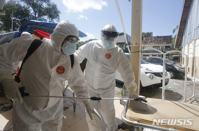 [AP/뉴시스] 15일 인니 발리에서 의료 종사자들이 코로나19 사망자를 옮긴 뒤 소독하고 있다