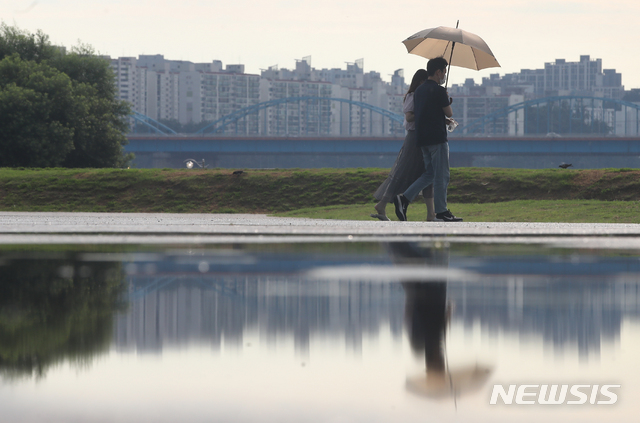 [서울=뉴시스] 조수정 기자 = 폭염 속 소나기가 내린 지난 15일 서울 서초구 반포지구 한강공원에서 시민들이 우산을 쓰고 걸어가고 있다. 2021.07.15. chocrystal@newsis.com