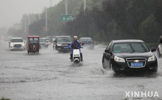 [정저우=신화/뉴시스]중국 허난성에 시간당 200㎜가 넘는 기록적인 폭우가 쏟아져 최소 12명이 숨졌다. 20일 물에 잠긴 정저우시 도심에 차량들이 오가고 있는 모습. 2021.07.21
