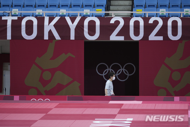 [도쿄=AP/뉴시스]23일 도쿄올림픽 유도 경기가 열리는 일본 도쿄 부도칸 경기장에서 한 직원이 올림픽 로고 아래를 걸어가고 있다. 도쿄올림픽은 이날 개막했다. 2021.07.23.