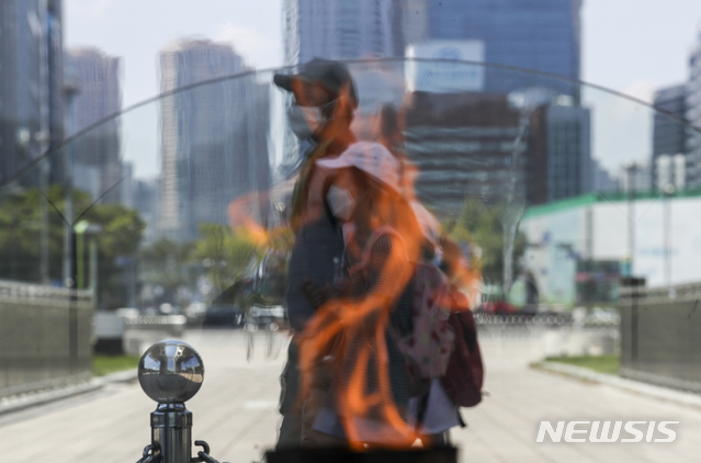 [서울=뉴시스] 정병혁 기자 = 폭염이 이어지고 있는 24일 오후 서울 송파구 올림픽공원 평화의문 성화 열기로 시민들의 모습이 일그러져 있다. 2021.07.24. jhope@newsis.com