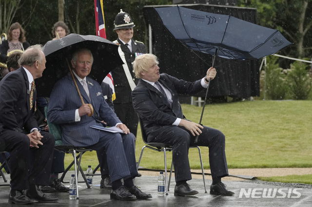 [알레와스(잉글랜드=AP/뉴시스]보리스 존슨 영국 총리(오른쪽)가 국립 추도 수목원에서 열린 경찰 기념비 제막식에서 뒤집어진 우산을 손보고 있다. 왼쪽은 찰스 왕세자. 2021.7.28.