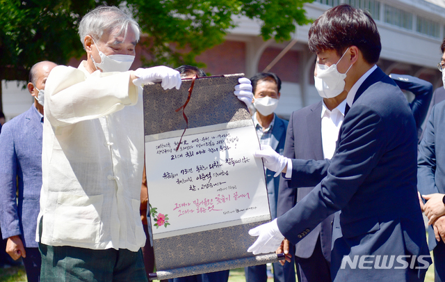 [순천=뉴시스] 류형근 기자 = 이준석 국민의힘 대표가 30일 오후 전남 순천시 순천팔마종합운동장에 설치된 여순항쟁탑 앞에서 여순사건유족회로부터 기념품을 받고 있다. 2021.07.30. hgryu77@newsis.com