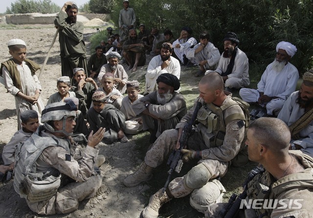 [AP/뉴시스] 2009년 7월 사진으로 아프가니스탄 현지인 통역이 미 해병대원 두 명과 헬만트주 마을 사람들 사이에 대화를 이어주고 있다. 