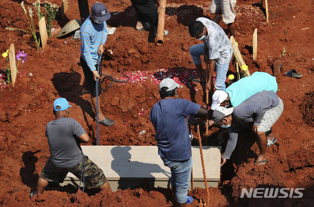 [자카르타=AP/뉴시스] 4일 인도네시아 수도 인근 공동묘지 코로나19 사망자묘역에서 사람들이 관을 내리고 있다.