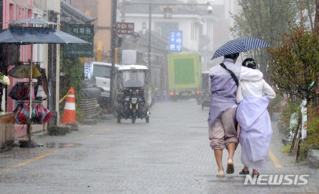 [전주=뉴시스] 김얼 기자 = 전북 전주시에 갑작스러운 집중호우가 내리기 시작한 12일 오후 전주한옥마을 향교 인근에서 관광객들이 우산으로 비를 피하며 발걸음을 옮기고 있다. 2021.08.12. pmkeul@newsis.com