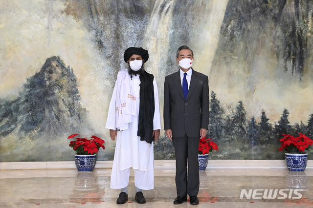 [텐진=AP/뉴시스] 중국이 아프가니스탄에 매장된 수조 달러 상당의 희토류를 노리고 탈레반과 협력할 수 있다고 17일(현지시간) CNBC가 분석했다. 사진은 지난 7월 왕이 중국 외교부장(오른쪽)이 탈레반의 정치 수장인 압둘 가니 바라다르(왼쪽)를 만난 모습. 2021.08.18.