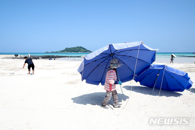 [제주=뉴시스] 우장호 기자 = 제주 지역 사회적 거리두기가 4단계로 격상된 18일 오전 제주시 한림읍 협재해수욕장에서 마을 관계자들이 파라솔을 정리하고 있다. 4단계 조치로 제주 도내 12개 지정 해수욕장은 오는 29일까지 모두 폐장한다. 2021.08.18. woo1223@newsis.com