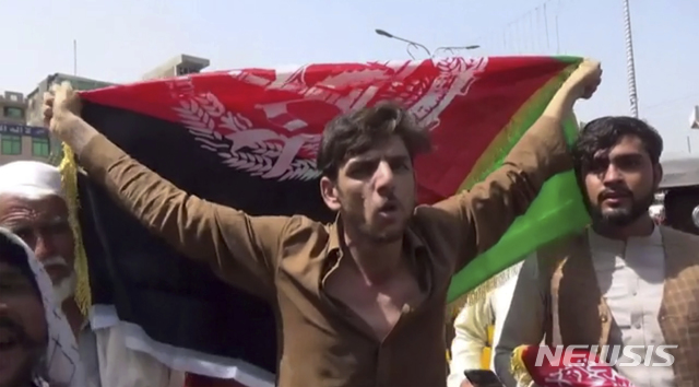 [잘라라바드(아프가니스탄)=AP/뉴시스]한 남성이 18일(현지시간) 아프가니스탄 잘라라바드에서 아프간 국기를 들고 있다. 이들은 탈레반의 상징인 흰 깃발을 내리고 국기로 교체하는 위를 벌이다 탈레반의 공격을 받았다. 2021.08.19. photo@newsis.com