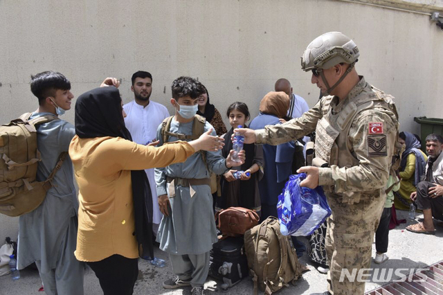 [카불(아프가니스탄)=AP/뉴시스] 지난 18일(현지시간) 터키 군인이 아프간 카불 공항에서 현지인들에게 물을 나눠주고 있다. 2021.08.26.