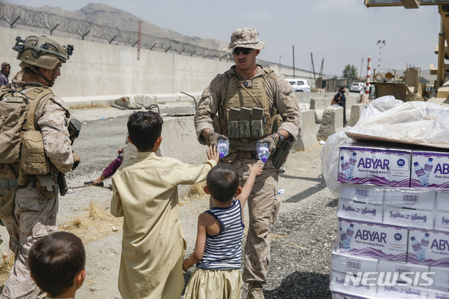 [카불=AP/뉴시스] 20일(현지시간) 아프가니스탄 카불의 하미드 카르자이 국제공항에서 한 미군 병사가 대피를 앞둔 아프가니스탄 어린이들에게 생수를 나눠주고 있다. 조 바이든 미국 대통령은 탈레반이 장악한 아프간에서 모든 미국인을 귀환시킬 것과 미국을 지원한 모든 아프간인을 대피시킬 것을 재차 다짐했다. 2021.08.21.