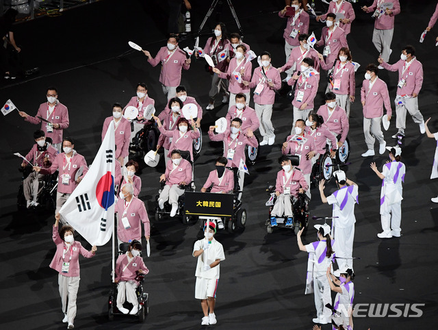 [도쿄(일본)=뉴시스] 사진공동취재단 = 2020 도쿄 패럴림픽 개회식이 24일 오후 8시 일본 도쿄 국립경기장(올림픽 스타디움)에서 열렸다. 대한민국 선수단이 입장하고 있다. 대한민국 선수단은 아프가니스탄 국기를 포함한 전체 163국 중 82번째로 입장했다. 한국의 자부심을 한껏 담아낸, 조선시대 당상관 관복의 훈색(분홍빛 계열) 저고리와 대님바지, 호랑이 문양과 금빛 동정을 새긴 한복을 입고 도쿄패럴림픽 도전에 나섰다. 기수는 보치아 대표팀의 최예진과, 그의 경기파트너인 어머니 문우영씨가 맡았다. 2021.08.24. photo@newsis.com