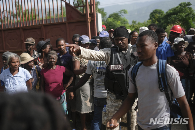[마니시=AP/뉴시스] 24일(현지시간) 아이티 마니시의 한 구호물자 배급소에서 현지 경찰이 몰려드는 주민들을 통제하고 있다. 2021.08.25.