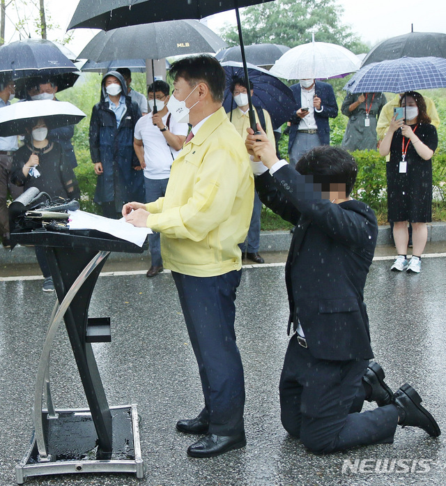 [진천=뉴시스] 강신욱 기자 = 강성국 법무부 차관이 27일 오후 충북혁신도시 국가공무원인재개발원 정문 앞에서 아프가니스탄 특별기여자 초기 정착 지원을 발표하는 브리핑을 하는 동안 한 직원이 뒤쪽에 무릎을 꿇고 우산을 받쳐주고 있다. 이날 강 차관이 발표한 브리핑 자료는 비가 흠뻑 젖었다. 2021.08.27. ksw64@newsis.com