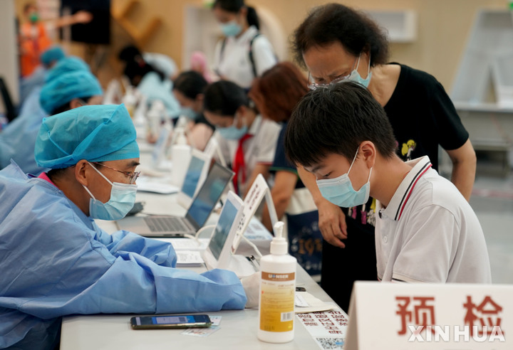 [상하이=신화/뉴시스] 중국 상하이 쉬후이구에 있는 코로나19 백신 접종센터에서 어린 학생이 백신을 맞기 전에 몸 이상 여부에 관한 질문에 답하고 있다. 상하이시 당국은 이날부터 12~14세 청소년에 대한 일제접종을 시작했다. 2021.09.05 