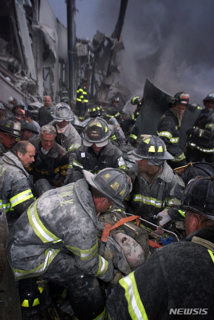 [뉴욕=AP/뉴시스] 2001년 9월 11일 미국 뉴욕 세계무역센터가 무너진 직후 소방관이 현장에서 구조되는 모습. 2021.09.10.