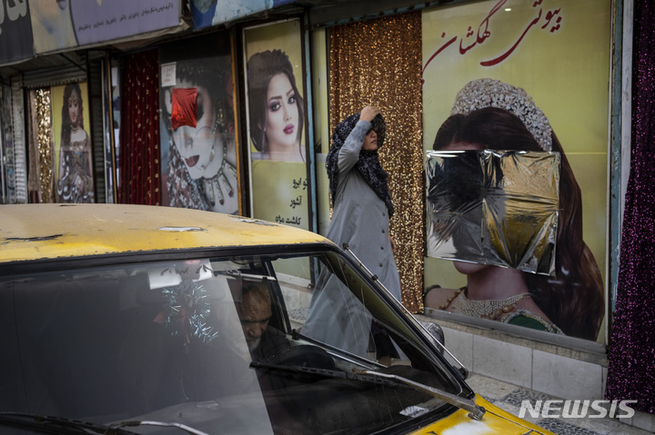 [카불=AP/뉴시스] 12일(현지시간) 아프가니스탄 카불에서 한 아프간 여성이 유리창 속 여성 사진이 은박지로 가려진 미용실을 지나가고 있다. 탈레반이 아프간을 장악한 이후, 미용실 외부를 장식했던 여성의 이미지들이 제거되거나 가림 처리됐다. 2021.09.13.