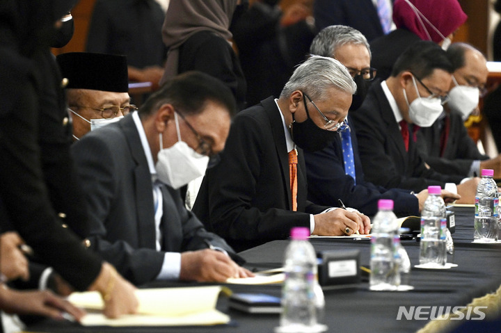 [AP/뉴시스] 13일 말레이시아의 이스마일 총리(가운데)와 야당지도자 안와르 의원(왼쪽)이 의회 개원과 함께 '협치' 양해각서에 서명하고 있다.