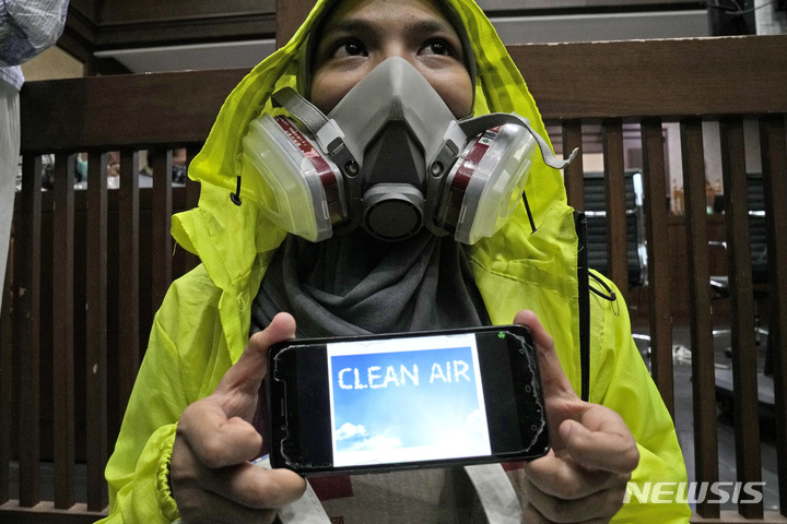[자카르타(인도네시아)=AP/뉴시스]인도네시아 수도 자카르타의 중앙자카르타 지방법원 앞에서 16일 마스크를 착용한 한 환경 운동가가 '청정한 공기'라고 표시한 자신의 핸드폰을 들고 시위를 벌이고 있다. 인도네시아 법원은 16일 조코 위도도 대통령을 비롯한 6명의 고위 관리들이 청정한 공기를 마실 시민들의 권리를 충족시키지 못하고 있다며 수도 자카르타의 공기 질 개선을 명령했다. 2021.9.16