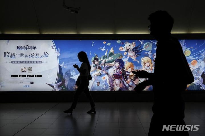 [베이징=AP/뉴시스] 중국 정부가 미성년자의 온라인 게임 접속 시간제한을 어긴 게임 회사를 고발할 수 있는 플랫폼을 개발했다. 사진은 지난 14일 베이징에 있는 한 지하철 역에 걸린 RPG게임 광고 앞으로 시민들이 걸어가는 모습. 2021.09.17. photo@newsis.com