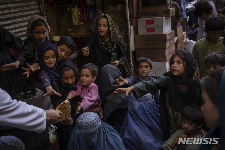 [카불=AP/뉴시스] 16일(현지시간) 아프가니스탄 카불의 한 빵집 앞에서 여성과 아이들이 나눠주는 빵을 받고 있다. 2021.09.17