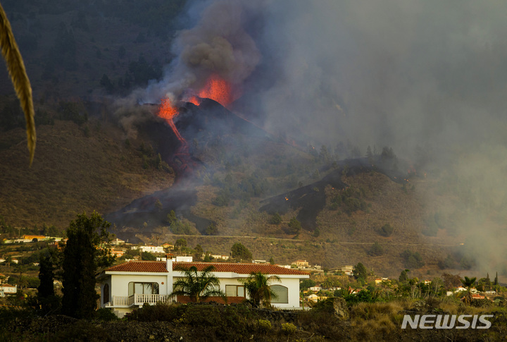 [라팔마=AP/뉴시스] 스페인 카나리아제도 라 팔마 섬에 있는 쿰브레 비에호 화산이 폭발해 19일(현지시간) 용암이 분출하며 흐르고 있다. 당국은 이 화산이 일주일간의 지진 활동 끝에 폭발해 분출된 용암이 가옥을 파괴하고 해안으로 접근하면서 수천 명의 주민에 대피령을 내렸다고 밝혔다. 2021.09.20.