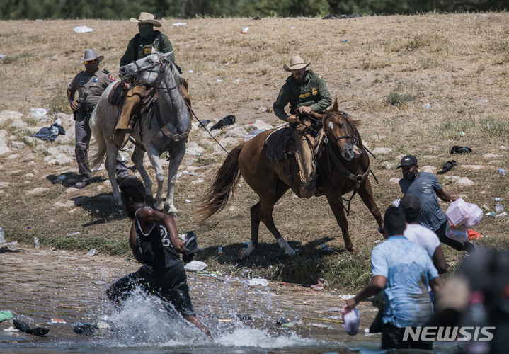 [텍사스(미국)=AP/뉴시스] 지난 19일(현지시간) 미국 기마경찰들이 멕시코 시우다드아쿠냐에서 리오그란데 강을 건너 텍사스 델 리오에 도착한 아이티 이주민들을 저지하고 있다. 2021.09.24.