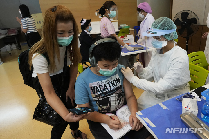 [방콕(태국)=AP/뉴시스]태국 방콕의 한 병원에서 21일 코로나19 백신을 접종받은 한 아이의 어머니가 옆에서 아들에게 휴대전화 화면을 보여주고 있다. 태국 보건 당국이 21일 기저질환이 있는 12∼18세의 아이들에게 화이자의 코로나19 백신을 접종하기로 결정했다. 2021.9.21