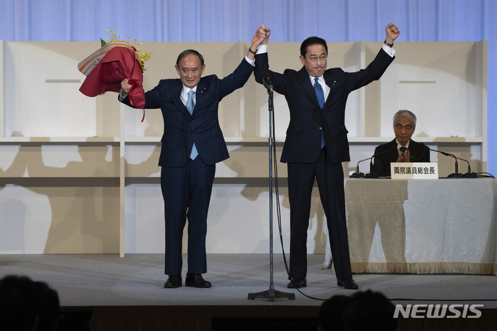 [도쿄(일본)=AP/뉴시스]29일 일본 도쿄에서 열린 집권 자민당 총재선거에서 기시다 후미오 전 정조회장(오른쪽)이 승리한 후 스가 요시히데 총리와 손을 들어보이고 있다. 기시다 신임 총재는 내달 4일 총리 지명을 거쳐 제 100대 일본 총리로 취임하게 된다. 2021.09.29.