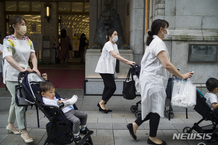 [도쿄=AP/뉴시스]일본 도쿄의 한 백화점 앞을 지나가는 육아여성. 2023.03.31.