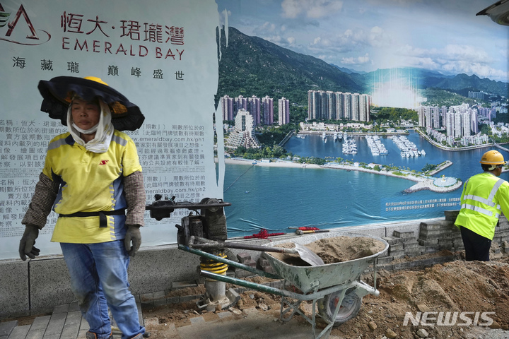 [홍콩=AP/뉴시스] 지난 4일 한 작업자가 헝다 그룹 홍콩 본부에 붙은 부동산 프로젝트 홍보 사진을 지나가고 있다. 2021.10.20.