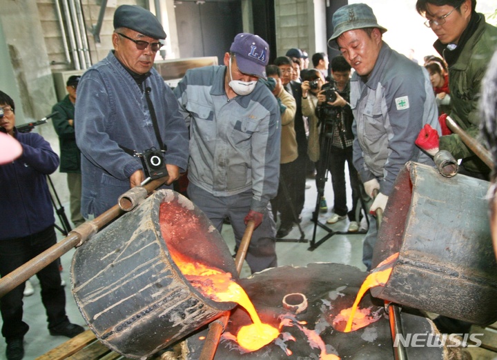 [진천=뉴시스] 강신욱 기자 = 충북 진천군 덕산읍 성종사는 22일부터 24일까지 범종 전통 주조기술을 공개 시연한다. 원광식(왼쪽) 주철장이 마지막 주조 과정에서 직접 거푸집에 용해한 청동을 주입하고 있다. 사진은 2011년 공개 시연행사. 2021.10.21. ksw64@newsis.com