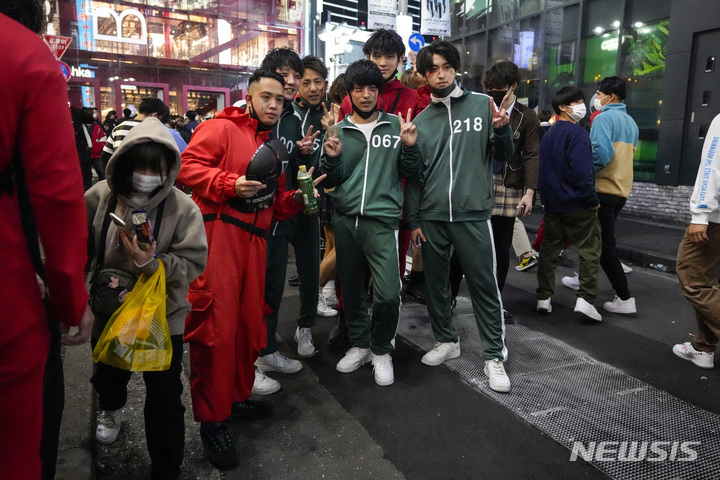 [도쿄=AP/뉴시스] 10월31일(현지시간) 일본 도쿄의 핼러윈 인기 모임 장소인 시부야구에 수천 명이 모인 동안 오징어게임 복장을 한 핼러윈 참가자들이 기념사진을 찍고 있다. 2021.11.01.