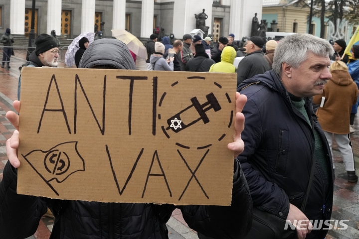 [키예프=AP/뉴시스] 3일(현지시간) 우크라이나 수도 키예프에서 백신 접종 의무화 반대 시위가 열려 한 참가자가 '백신 반대'라고 쓰인 손팻말을 들고 있다. 우크라이나 당국은 코로나19 확산을 막기 위해 교사, 공무원, 기타 근로자들에게 오는 8일까지 백신 접종을 완료하지 않으면 급여 지급을 중단한다고 밝혔다. 우크라이나는 비행기, 기차, 장거리 버스 등에 탑승하기 위해서는 백신 패스나 코로나19 검사 음성 확인서를 지참해야 한다. 2021.11.03.