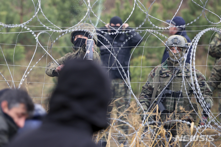 [그로드노(벨라루스)=AP/뉴시스] 8일(현지시간) 폴란드와 벨라루스 국경 그로드노에서 폴란드 국경수비대와 난민들이 대치하고 있다. 2021.11.09.