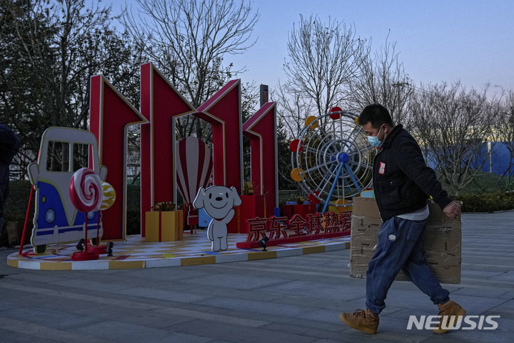 [베이징=AP/뉴시스] 중국 연중 최대 쇼핑축제인 광군제(독신절·11월11일)가 올해는 조용한 분위기에서 진행된다. 9일 중국 전자상거래 업체인 징둥 닷컴의 베이징 본사에서 한 직원이 광군제 홍보물 앞을 지나가고 있다. 2021.11.11 
