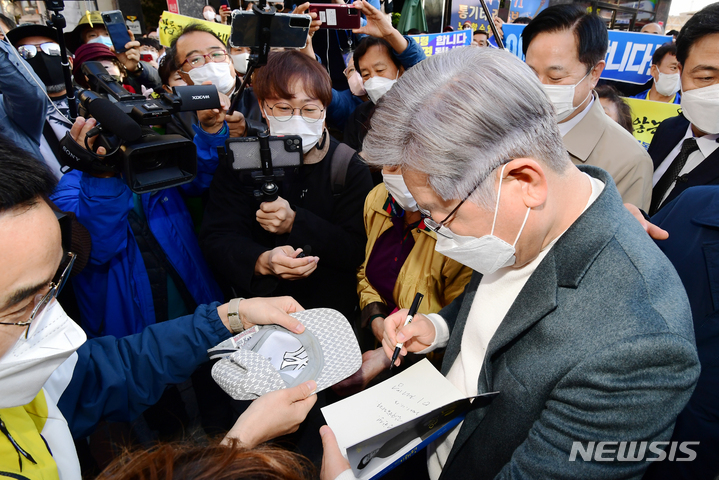 [창원=뉴시스] 차용현 기자 = 매타버스(매주 타는 민생버스)를 타고 전국순회에 나선 더불어민주당 이재명 대통령후보가 13일 오후 경남 창원시 3·15 의거 발원지 기념관앞에서 지지자가 내민 자신의 자서전에 사인을 하고 있다. 2021.11.13. con@newsis.com