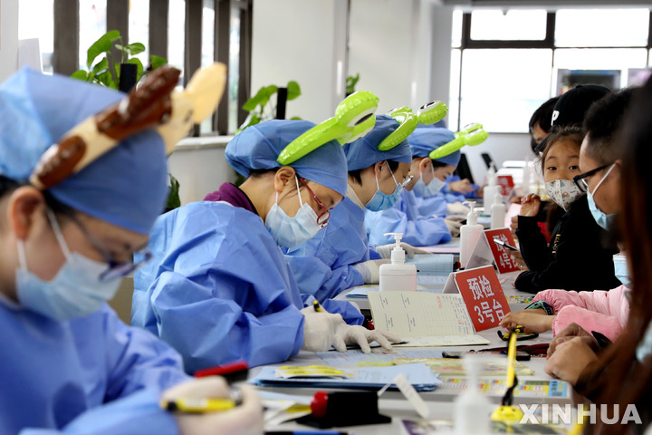 [상하이=신화/뉴시스] 중국 상하이 쉬후이구 접종센터에서 20일 보건노동자들이 만화 캐릭터를 머리에 장식하고서 3~5세 어린이를 맞아 백신을 투여하고 있다. 2021.11.21