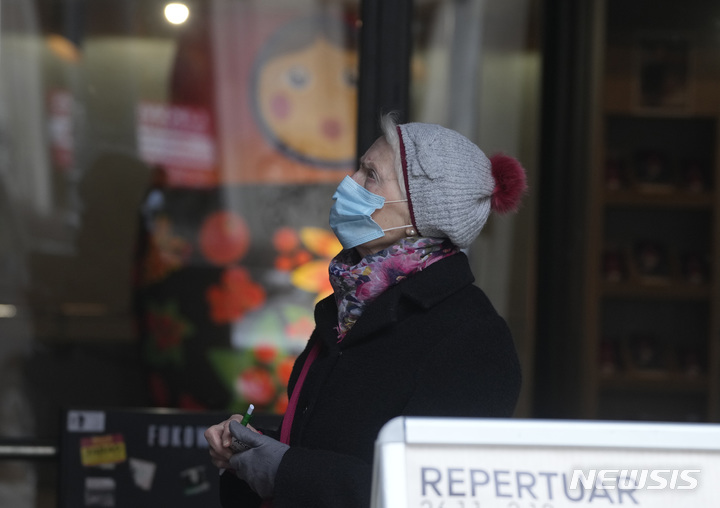 [바르샤바=AP/뉴시스] 11월26일(현지시간) 폴란드 수도 바르샤바에서 마스크를 쓴 고령층 여성이 길을 걸으며 위를 올려다 보고 있다. 2021.12.01.