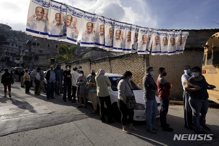 [테구시갈파( 온두라스)= AP/뉴시스] 온두라스의 수도 테구시갈파에서 28일 유권자들이 투표소 앞에 길게 줄을 서서 대기하고 있다.  