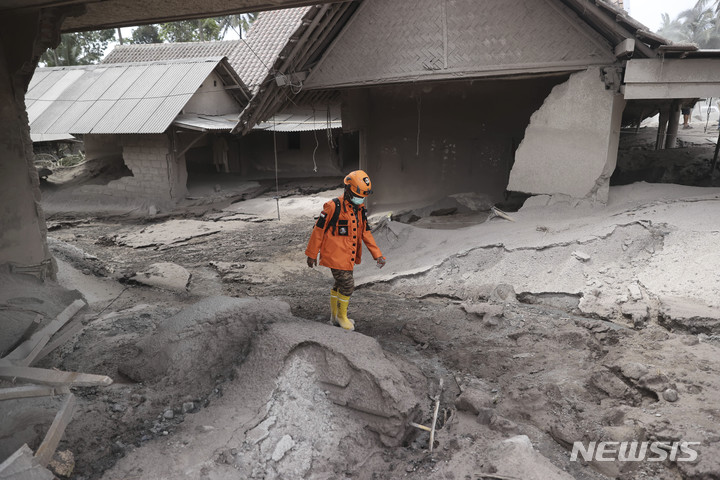 [자바(인도네시아)=AP/뉴시스]5일 인도네시아 자바섬 동부에 위치한 스메루 산이 분화한 가운데 구조대원이 피해 현장을 살펴보고 있다. 2021.12.06.
